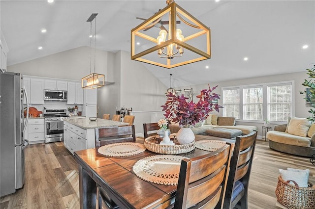 dining room featuring high vaulted ceiling, recessed lighting, light wood-type flooring, and a notable chandelier