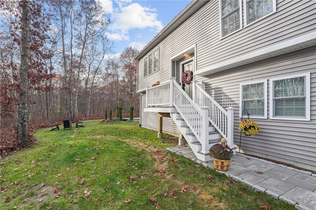 view of side of property with stairs and a lawn