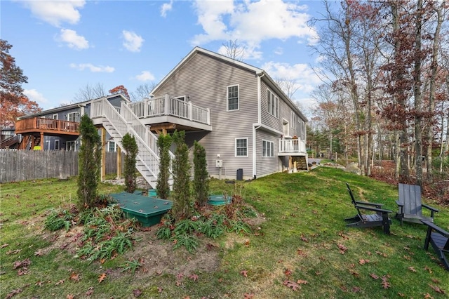 rear view of house featuring stairs, a yard, a deck, and fence