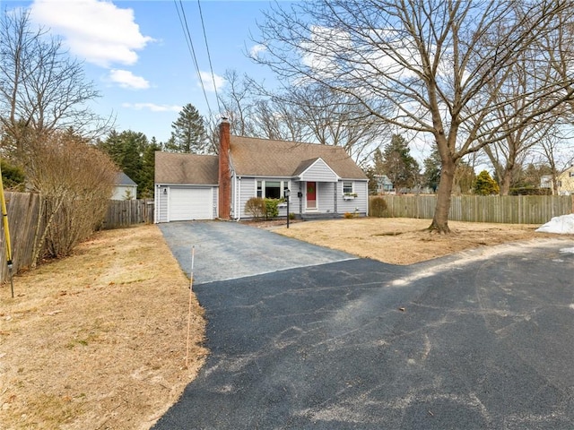 view of front facade featuring a garage, aphalt driveway, a chimney, and fence