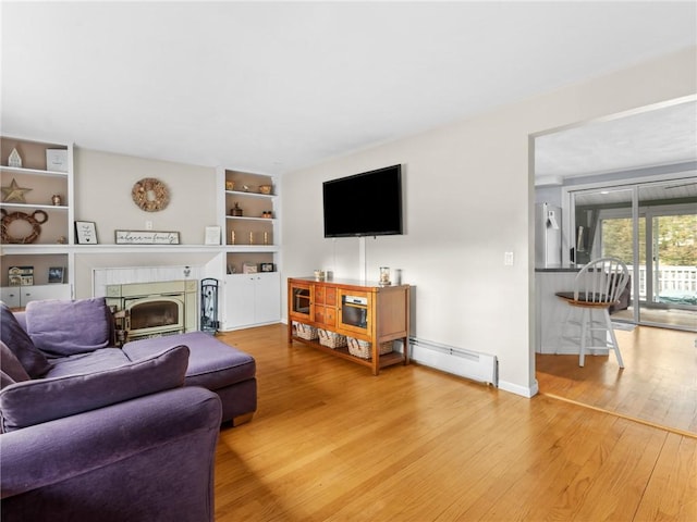 living room with a fireplace, baseboards, baseboard heating, and wood finished floors