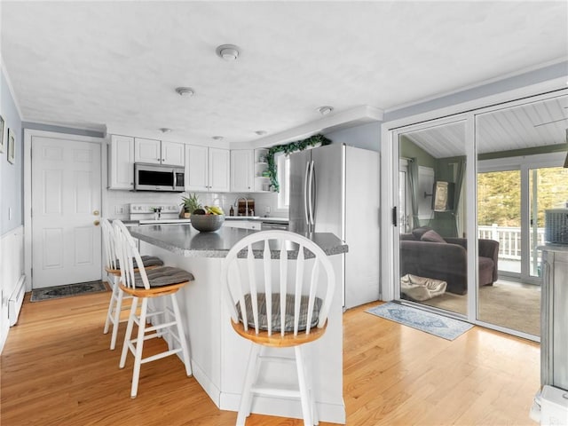 kitchen with light wood-style flooring, stainless steel appliances, a breakfast bar, a kitchen island, and a sink