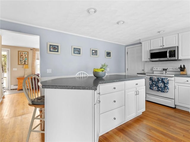 kitchen featuring a breakfast bar, a kitchen island, light wood finished floors, stainless steel microwave, and white electric range oven