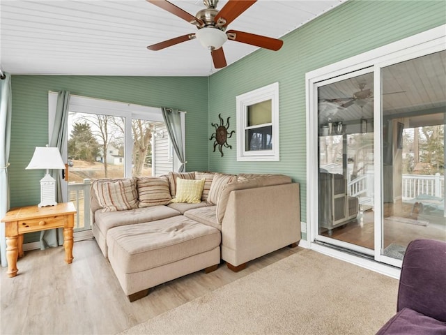 living area featuring lofted ceiling, plenty of natural light, a ceiling fan, and wood finished floors