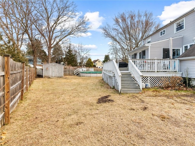 view of yard featuring a deck, an outbuilding, a fenced backyard, a fenced in pool, and a shed