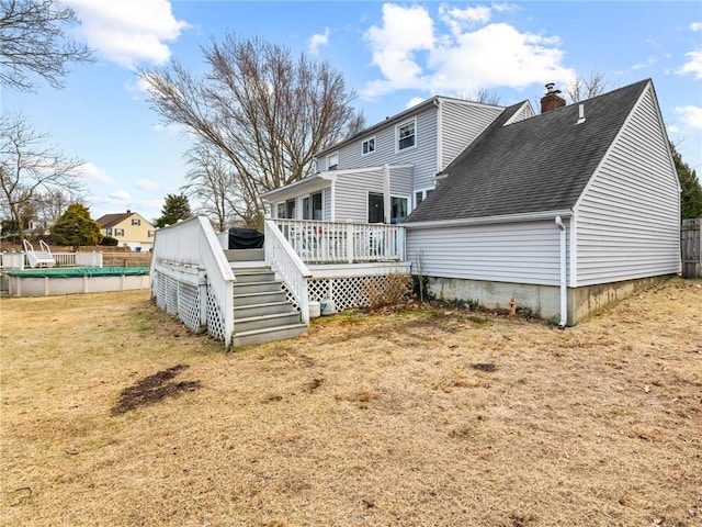 back of property featuring a deck, a shingled roof, fence, a fenced in pool, and a chimney