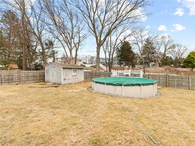 view of yard featuring a storage shed, a fenced backyard, a fenced in pool, and an outbuilding