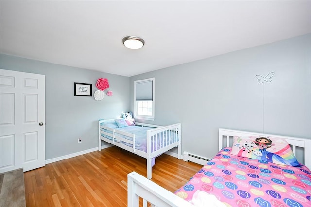 bedroom with baseboard heating, baseboards, and wood finished floors