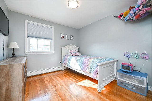 bedroom featuring light wood finished floors and baseboard heating