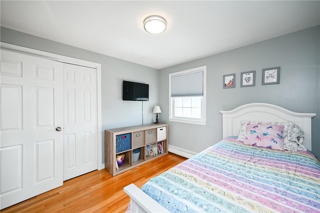 bedroom featuring a closet, baseboards, baseboard heating, and wood finished floors