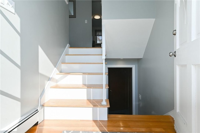 stairway featuring a high ceiling and a baseboard heating unit