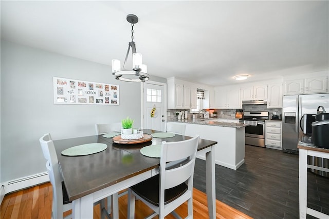 dining space featuring a baseboard heating unit, dark wood-style flooring, and a notable chandelier