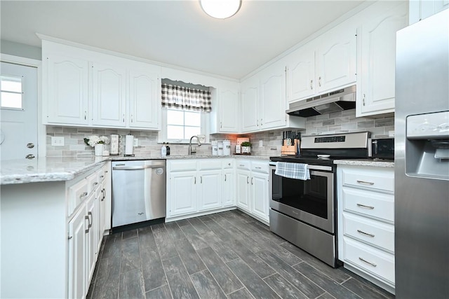 kitchen featuring tasteful backsplash, stainless steel appliances, under cabinet range hood, white cabinetry, and a sink