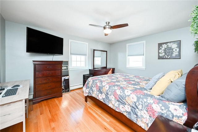 bedroom with ceiling fan, baseboard heating, multiple windows, and light wood-type flooring