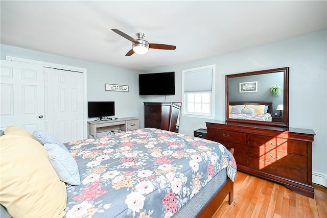 bedroom with a baseboard heating unit, a closet, a ceiling fan, and light wood-style floors