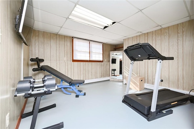 workout room with a paneled ceiling and wooden walls