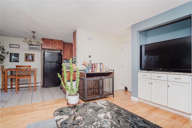 interior space with a chandelier, white cabinets, baseboard heating, freestanding refrigerator, and light wood finished floors