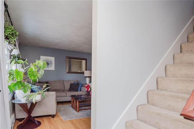 stairway with baseboard heating and wood finished floors