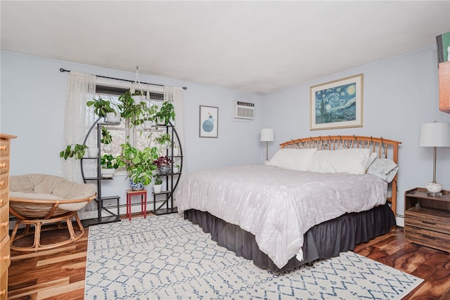 bedroom featuring baseboard heating, a wall unit AC, and wood finished floors