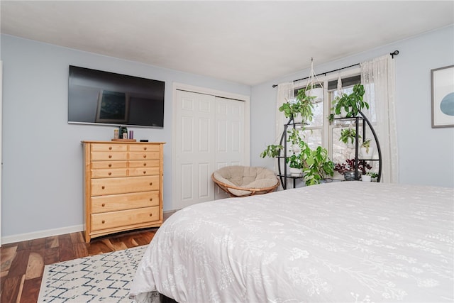 bedroom featuring a closet, dark wood-style flooring, and baseboards