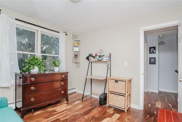 miscellaneous room featuring a baseboard heating unit, baseboards, and wood finished floors