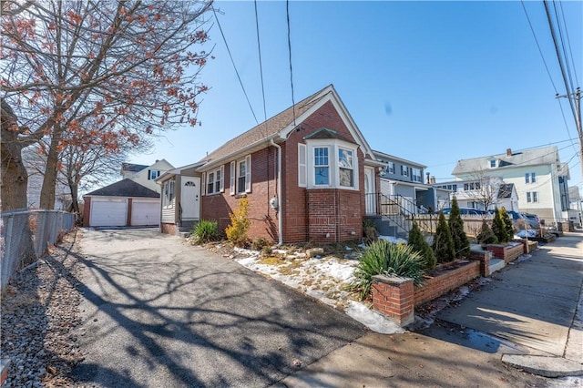 view of front facade with a garage, a residential view, an outbuilding, fence, and brick siding