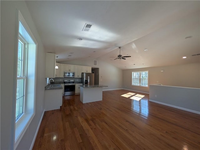 kitchen with lofted ceiling, open floor plan, dark wood-type flooring, a center island, and stainless steel appliances