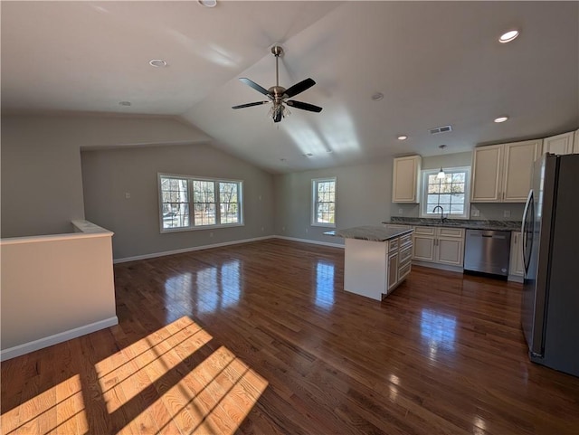 kitchen with baseboards, dark wood finished floors, dark countertops, appliances with stainless steel finishes, and a sink