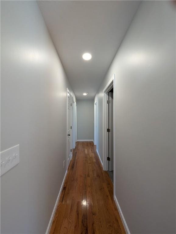 corridor featuring baseboards and wood finished floors