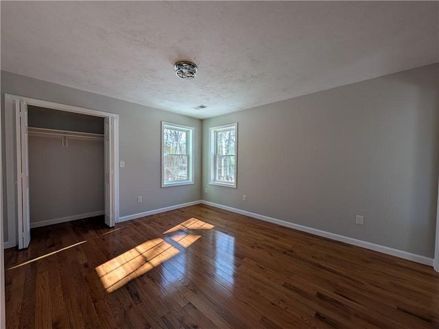 unfurnished bedroom with visible vents, baseboards, dark wood finished floors, a textured ceiling, and a closet