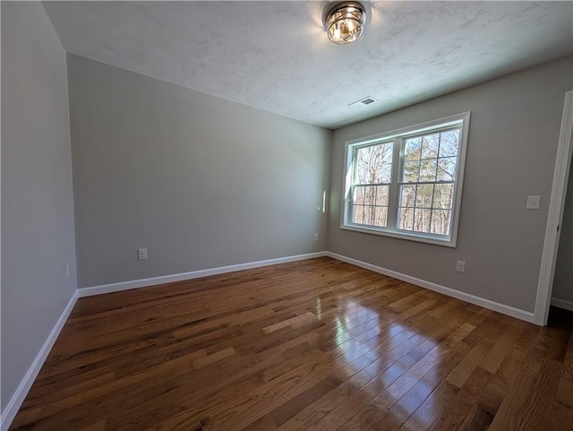 spare room with dark wood-style floors and baseboards