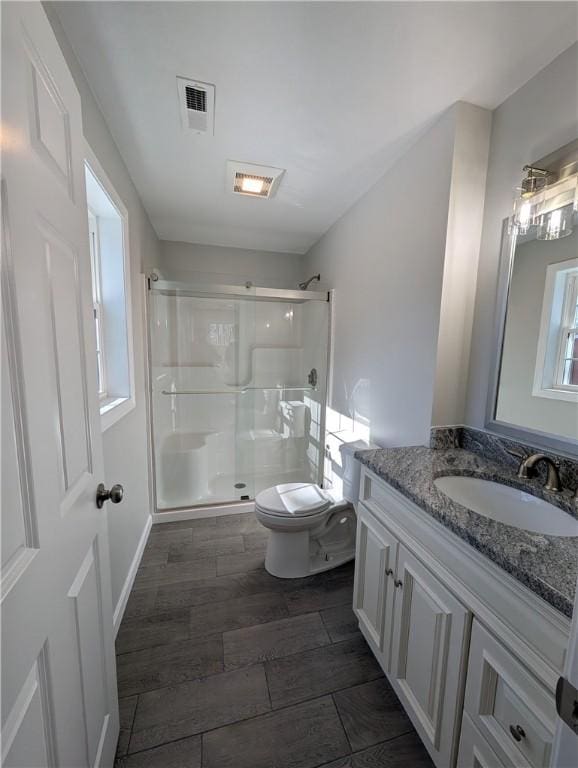 full bath featuring a stall shower, visible vents, toilet, vanity, and wood finish floors