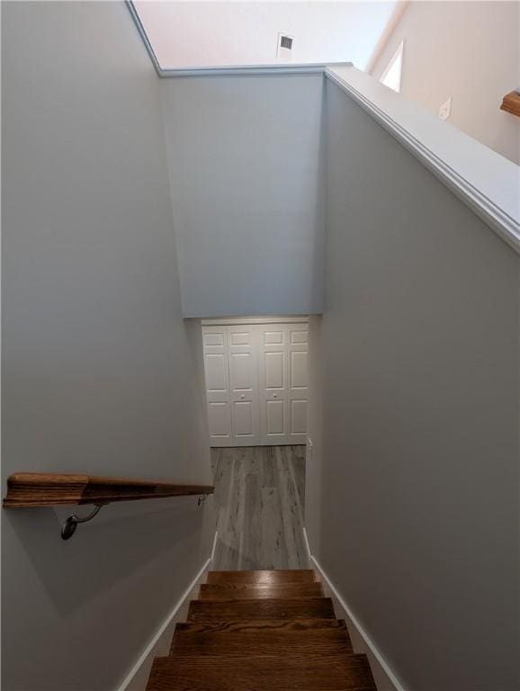 stairway with visible vents, baseboards, and wood finished floors