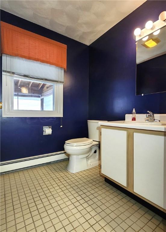 half bath featuring toilet, a baseboard heating unit, and vanity