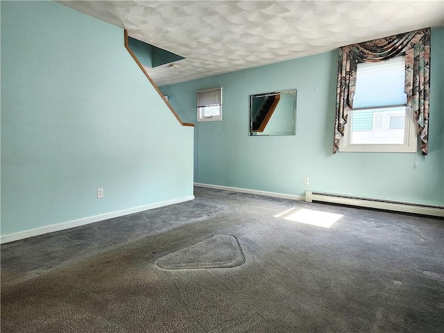 spare room with baseboard heating, carpet, and baseboards