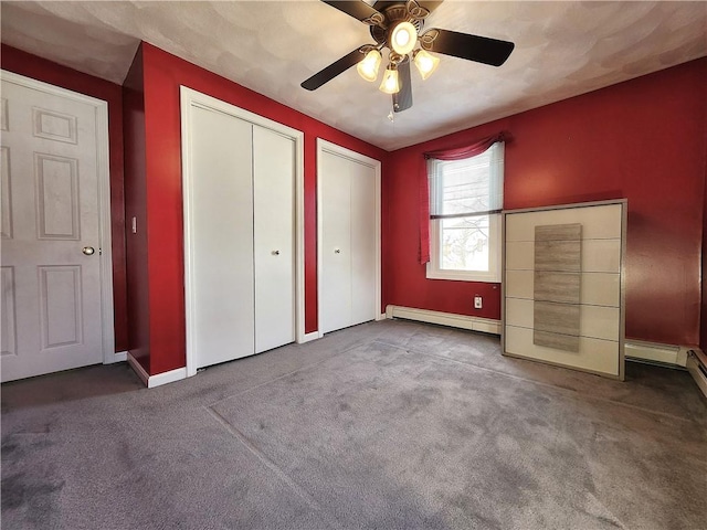 unfurnished bedroom featuring baseboards, ceiling fan, carpet, a baseboard heating unit, and two closets