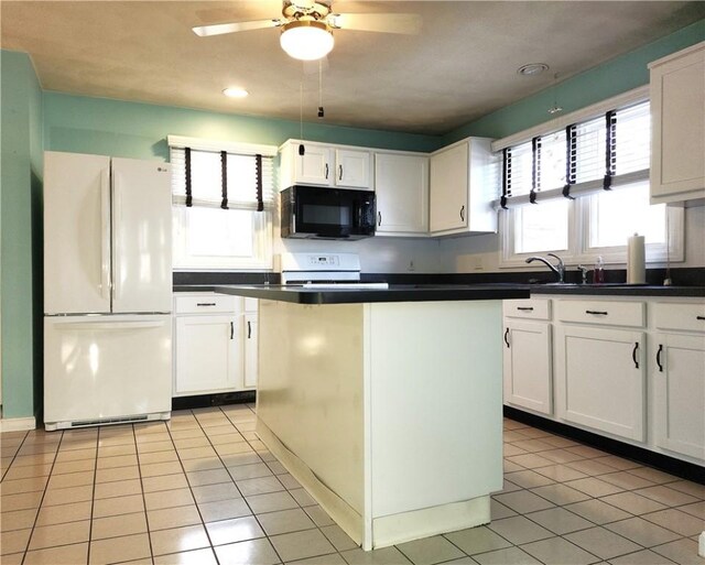 kitchen featuring black microwave, range with electric cooktop, white cabinetry, freestanding refrigerator, and dark countertops