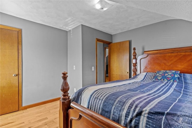 bedroom featuring a textured ceiling, light wood finished floors, and baseboards