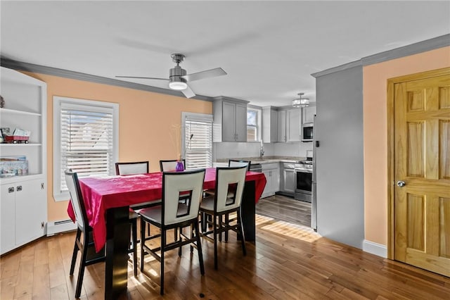 dining area with ornamental molding, a baseboard radiator, wood-type flooring, and a ceiling fan