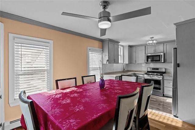 dining space featuring ceiling fan, light wood-type flooring, ornamental molding, and a baseboard radiator