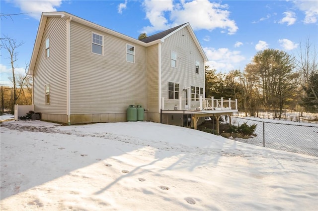 snow covered rear of property featuring fence and a deck