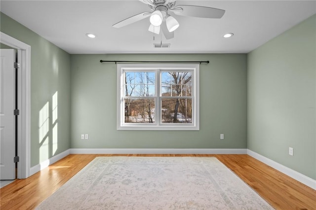 spare room with baseboards, visible vents, and light wood finished floors