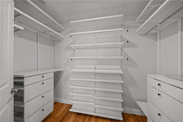 walk in closet with wood finished floors