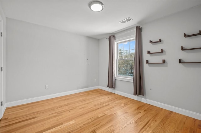 unfurnished room featuring light wood-type flooring, visible vents, and baseboards