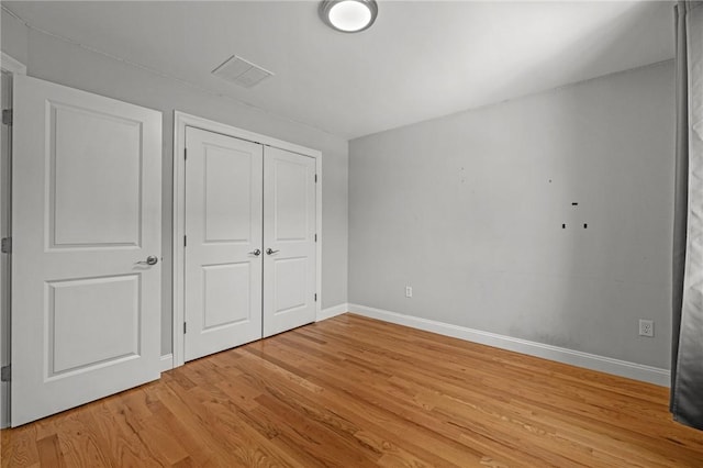 unfurnished bedroom featuring visible vents, a closet, light wood-style flooring, and baseboards