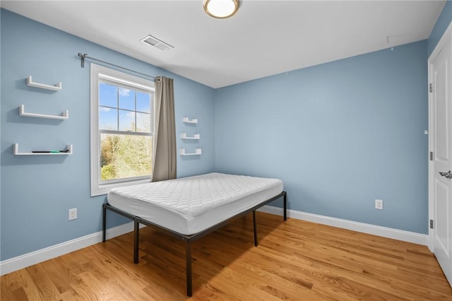 bedroom featuring baseboards, visible vents, and light wood-style floors