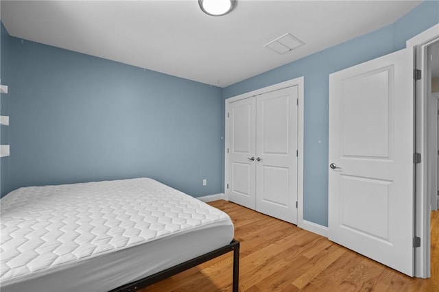 bedroom with light wood-style floors, a closet, visible vents, and baseboards