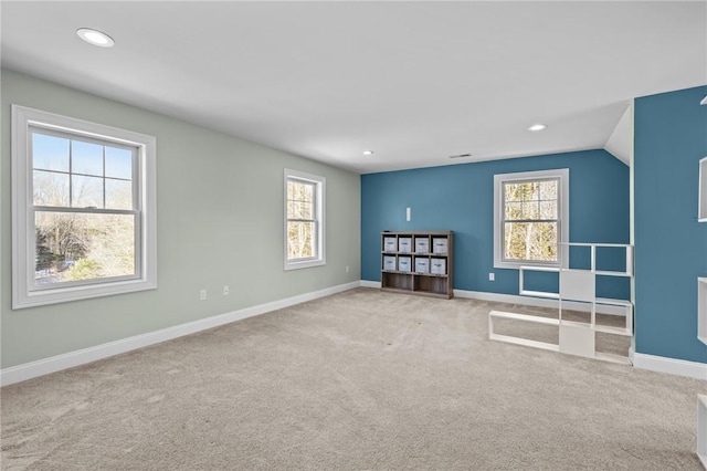 unfurnished room featuring plenty of natural light, baseboards, and light colored carpet