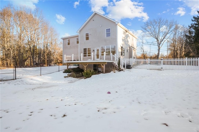 snow covered rear of property with a deck and fence