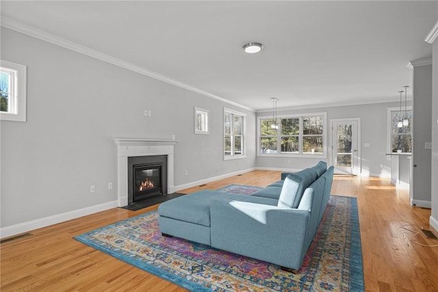 living room with a fireplace with flush hearth, ornamental molding, wood finished floors, and baseboards